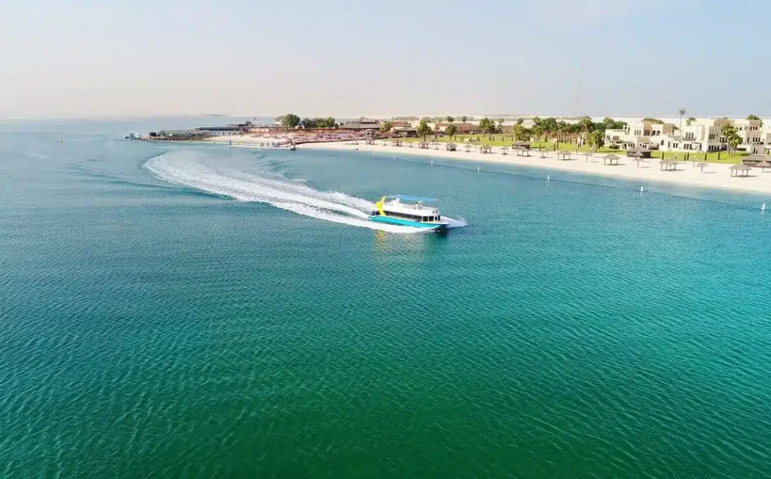 Passenger boat approaching Al Maya island resort in Abu Dhabi with pristine beach in background