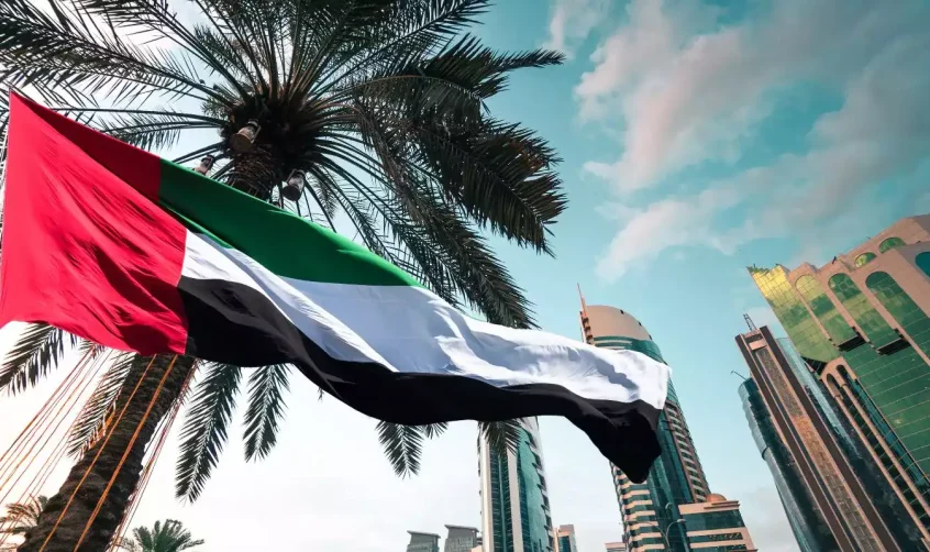 Die Nationalflagge der Vereinigten Arabischen Emirate weht neben Palmen und modernen Wolkenkratzern in Abu Dhabi und symbolisiert die Feierlichkeiten zum Scheich-Zayed-Festival.