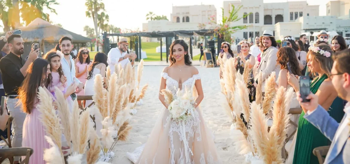 Bride walking down the aisle at Al Maya Island Resort, surrounded by pampas grass and guests at a luxurious Abu Dhabi wedding