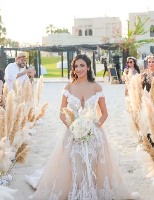 Braut schreitet den Gang hinunter im Al Maya Island Resort, umgeben von Pampasgras und Gästen einer luxuriösen Hochzeit in Abu Dhabi.