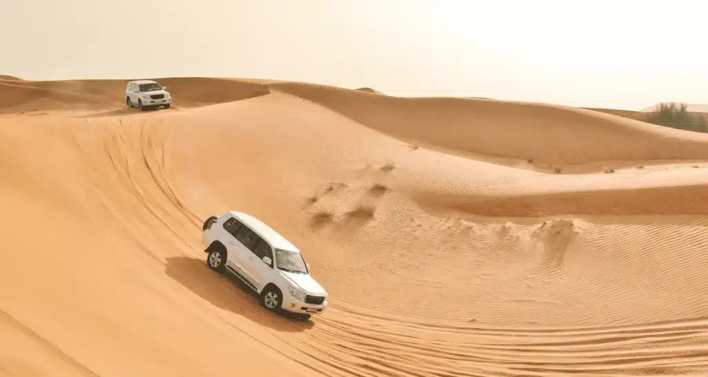 SUVs fahren bei einer Wüstensafari in Sharjah über Dünen.