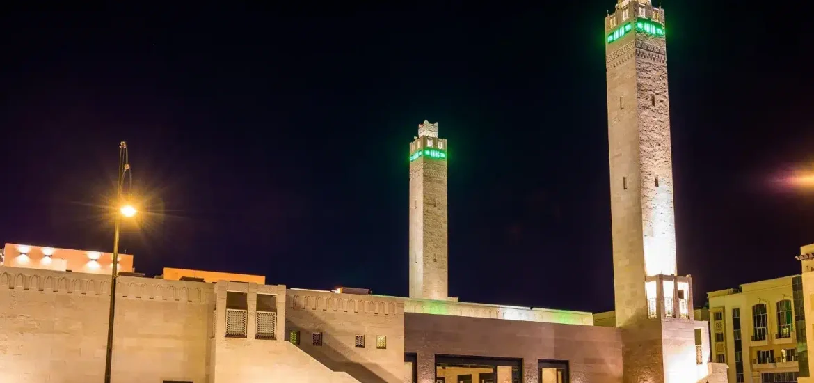 Sheikha Salama Mosque in Al Ain illuminated at night with its tall minarets and traditional Islamic architecture