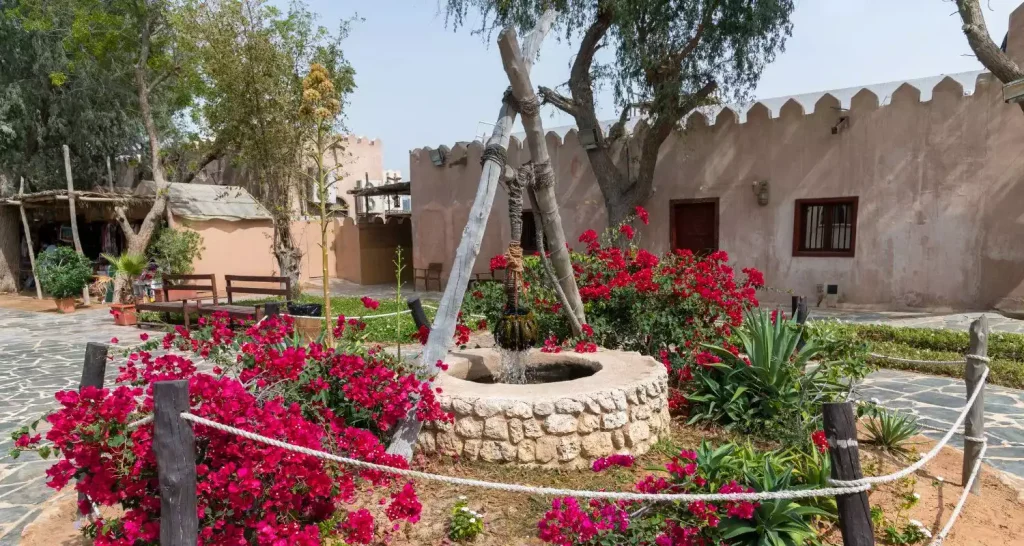 Traditioneller Brunnen, umgeben von Blumen, im Heritage Village in Abu Dhabi