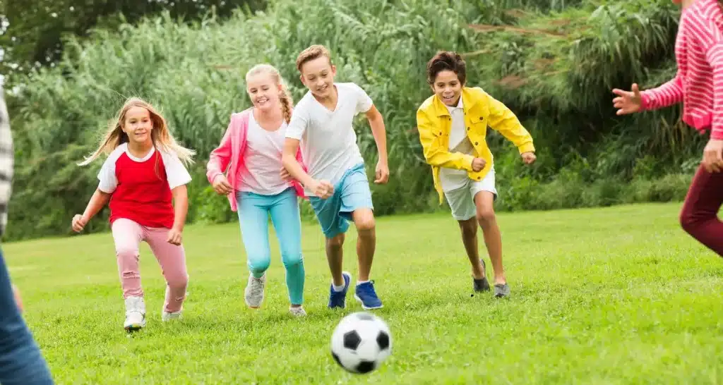Kinder spielen Fußball auf den Rasenflächen von Green Mubazzarah, dem beliebten Familienpark von Al Ain.