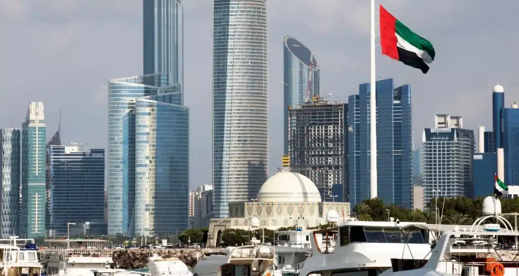 Die Flagge der Vereinigten Arabischen Emirate weht über der Al Bateen Marina mit der Skyline von Abu Dhabi im Hintergrund.