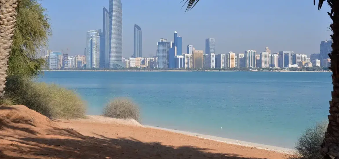 Blick auf die Strände von Abu Dhabi mit Skyline und türkisfarbenem Golfwasser, eingerahmt von Palmen.