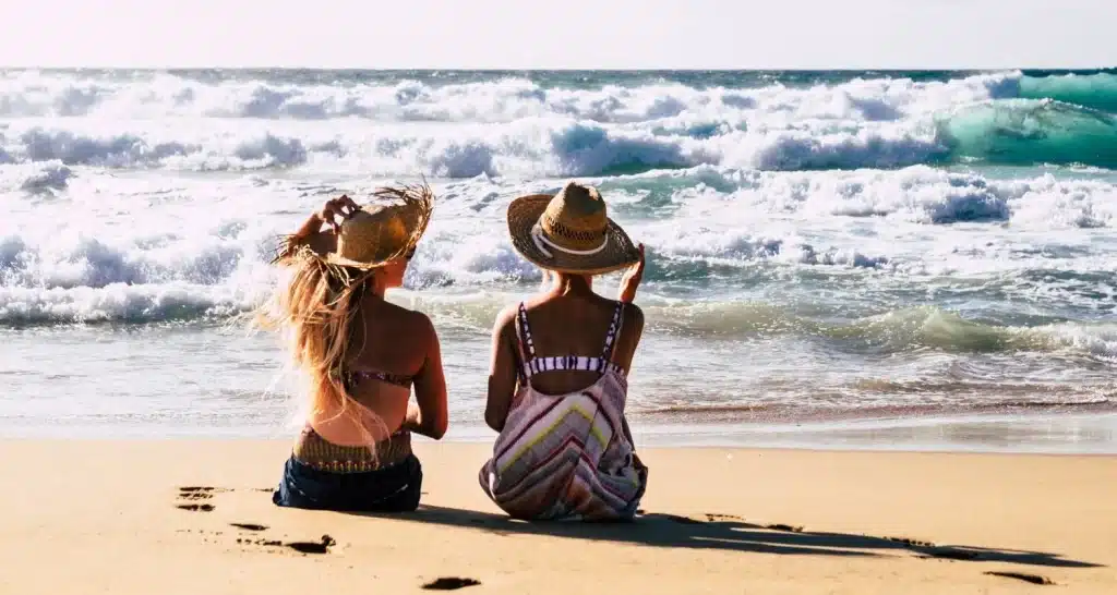 Frauen entspannen sich am Al Bateen Ladies Beach in Abu Dhabi im Sand, während im Hintergrund die Wellen rauschen.