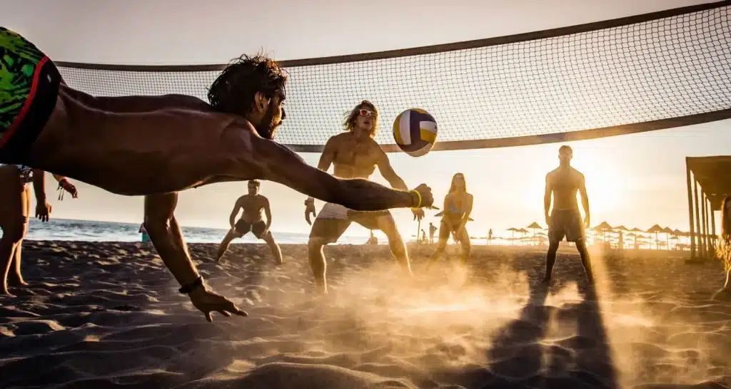 Beachvolleyballspiel bei Sonnenuntergang an den Stränden von Abu Dhabi mit goldenem Sand und Spielern in Aktion.