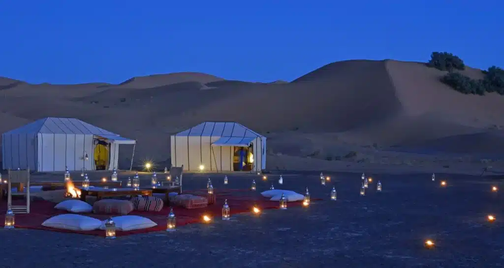 Luxuriöses Wüstencamp in der Nähe von Abu Dhabi für Silvesterfeierlichkeiten, mit Sitzgelegenheiten im Beduinenstil und Laternen unter dem Sternenhimmel.