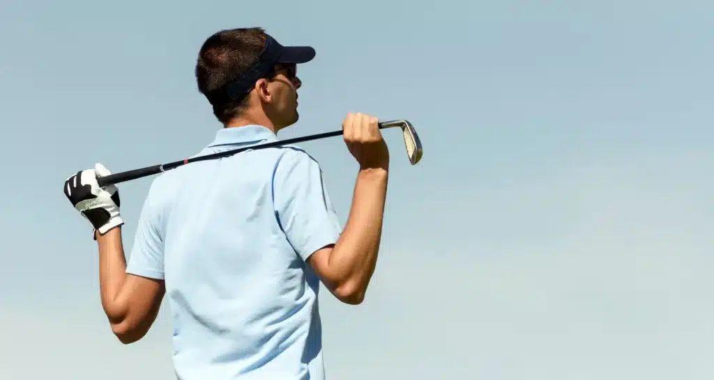 Golfer, der einen Schläger über die Schulter hält, während er den Platz im Abu Dhabi City Golf Club beobachtet.