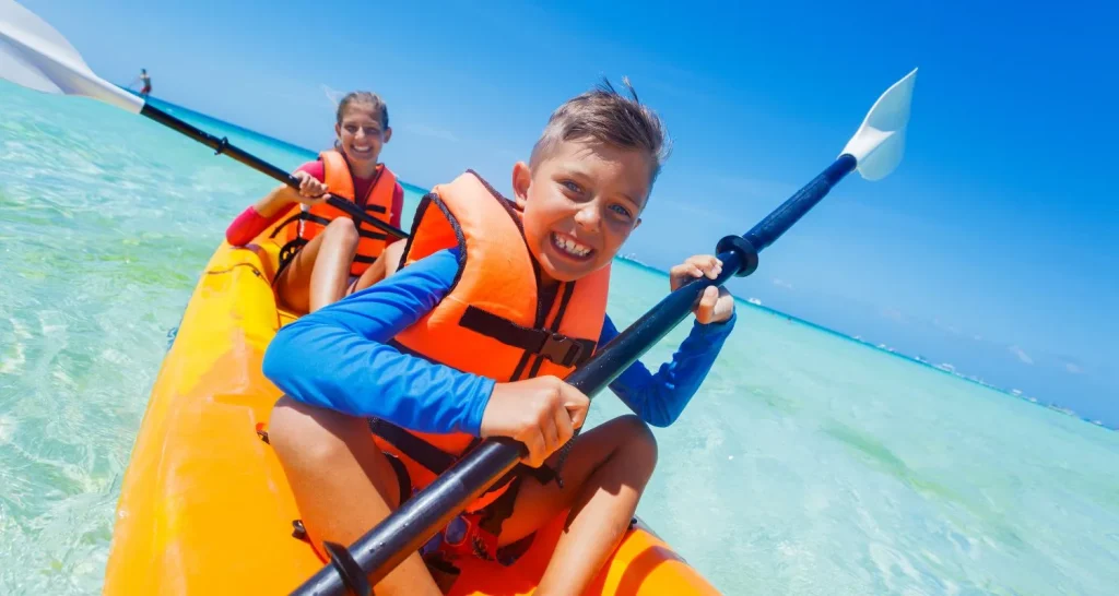 Familien-Kajakfahren am Al Bateen Beach in Abu Dhabi bei klarem, flachem Wasser an einem sonnigen Tag.