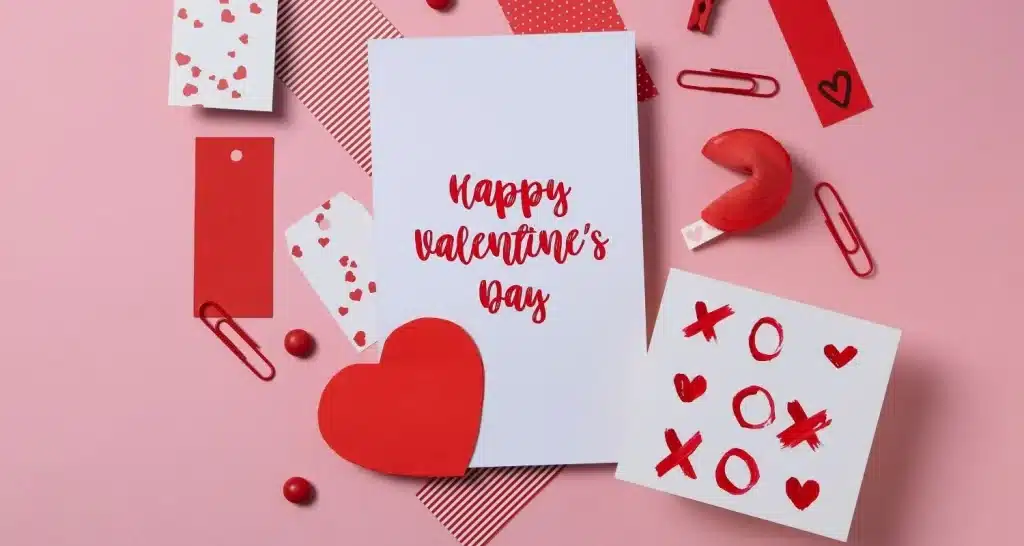 Flat Lay von Valentinstag-Karte mit Herzen, Notizen, und Dekorationen in roten und rosa Tönen