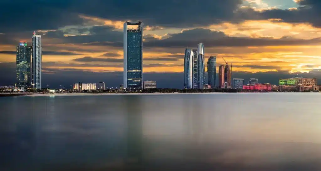 Die Skyline von Abu Dhabi bei Sonnenuntergang mit Blick auf die ruhige Uferpromenade.