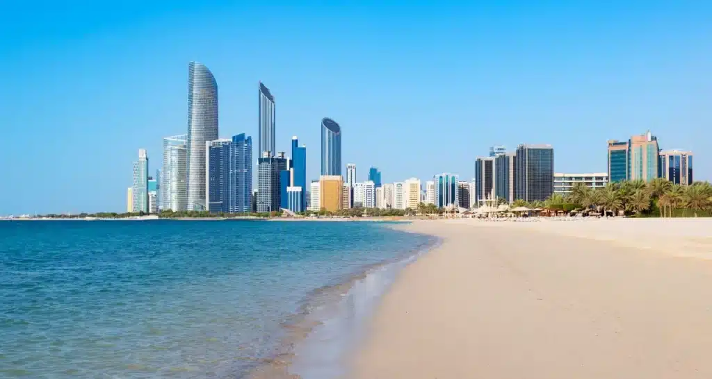 Sandiger Strandabschnitt der Corniche mit Wolkenkratzern entlang der Küstenlinie.